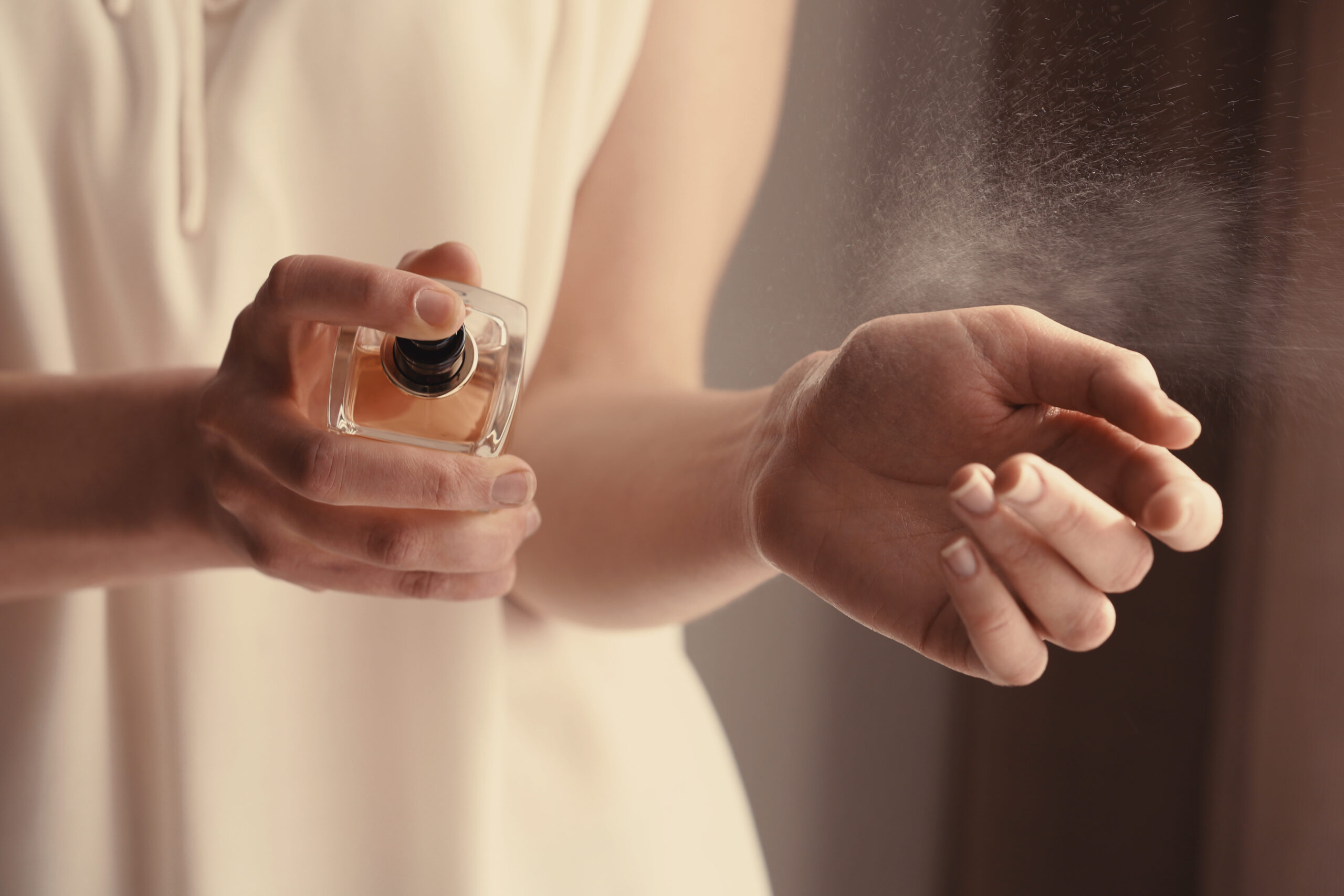 Beautiful young woman with bottle of perfume at home, closeup